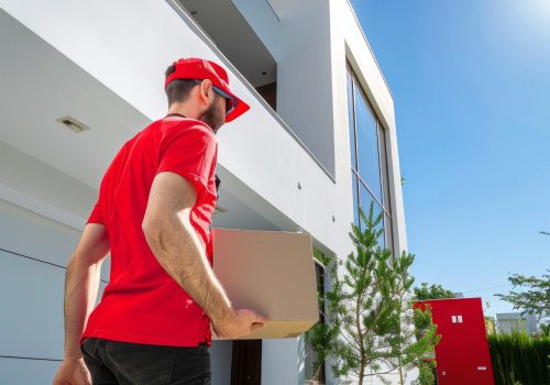 redshirted-delivery-man-bringing-box-door-modern-house